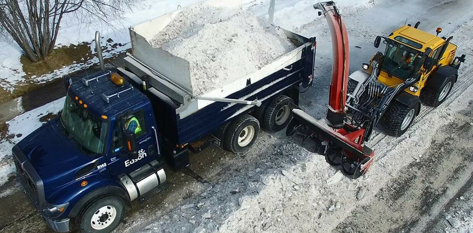 Snow blower loading a dump truck with snow